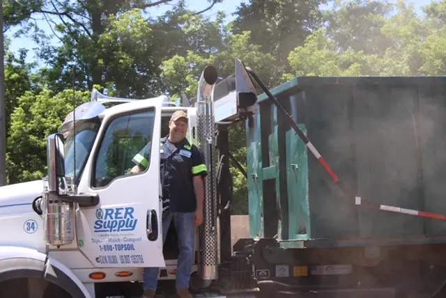 McGill/RER Supply driver standing beside his truck on a sunny day
