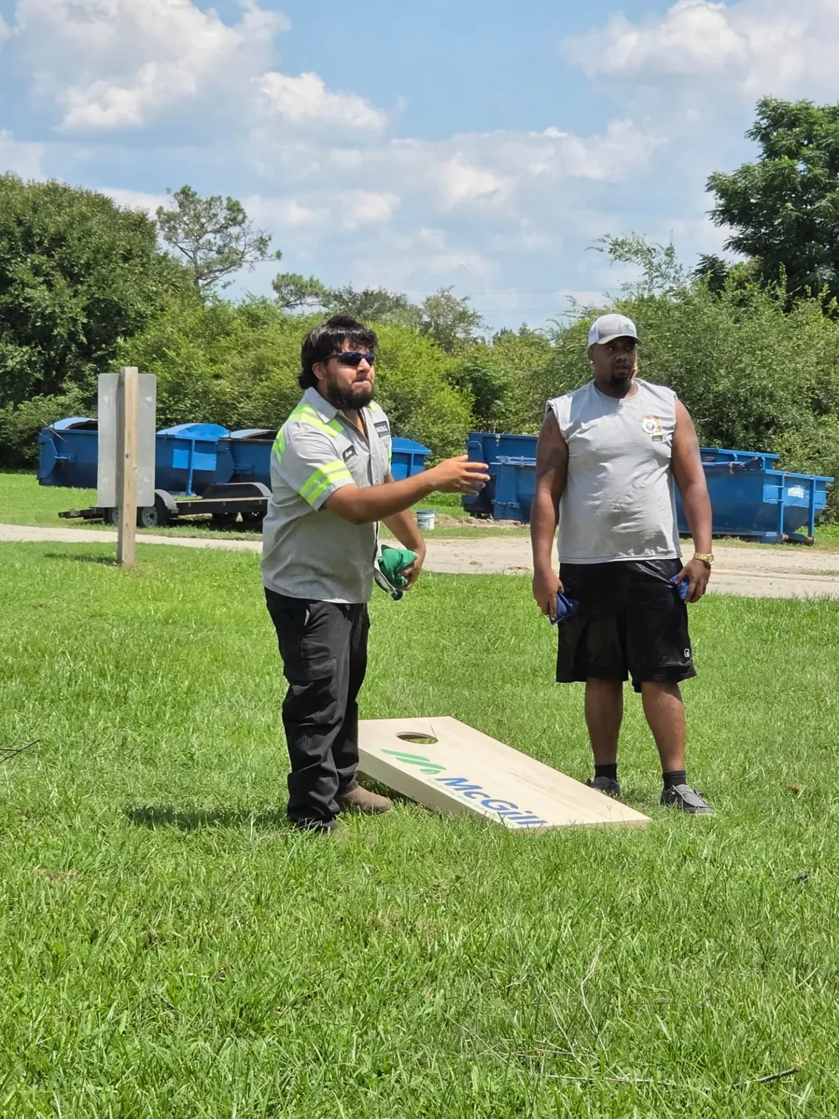 Two McGill team members playing cornhole with a branded board at a company outing